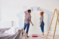 Un couple peint une maison sur un mur 