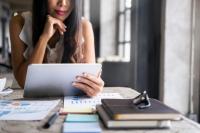 une femme regardant sa tablette avec des livres sur la table