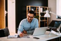 Un homme travaille devant son ordinateur portable et des graphiques.