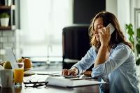 Une femme est au téléphone tout en regardant son ordinateur 