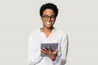 Une femme pianote sur sa tablette en souriant