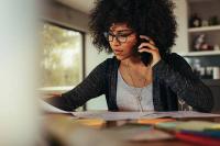 Une jeune femme téléphone tout en regardant un document