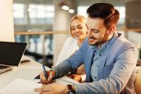 Un jeune couple signe un document dans un bureau