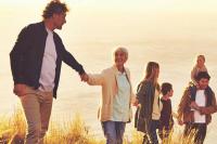 Des hommes, femmes et enfants se promènent au bord de la mer en se tenant par la main