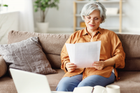 Une femme lit des documents sur son canapé