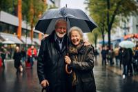 Un couple de séniors abrité avec un parapluie dans la rue