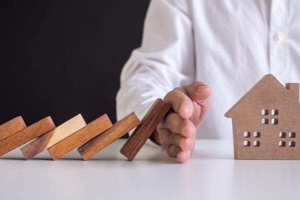 Une main retient des maisons en bois de tomber