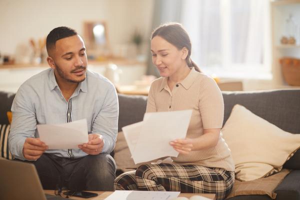 Un couple assit sur un canapé discute de documents