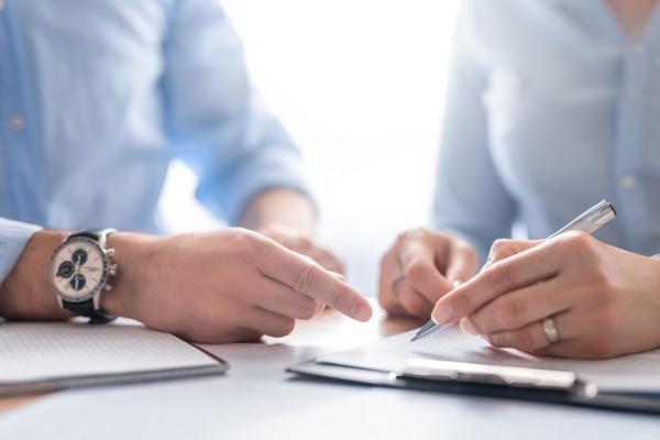 Les mains de deux personnes pointent un document