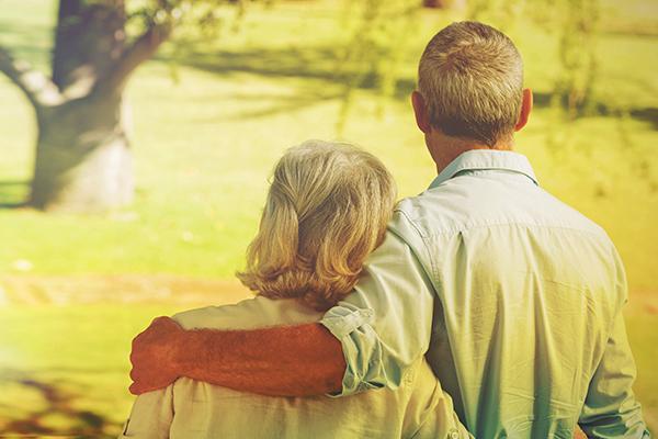 Un couple de personnes âgées regarde un arbre