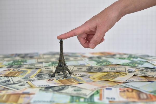 Une main touche une Tour Eiffel placée sur de nombreux billets