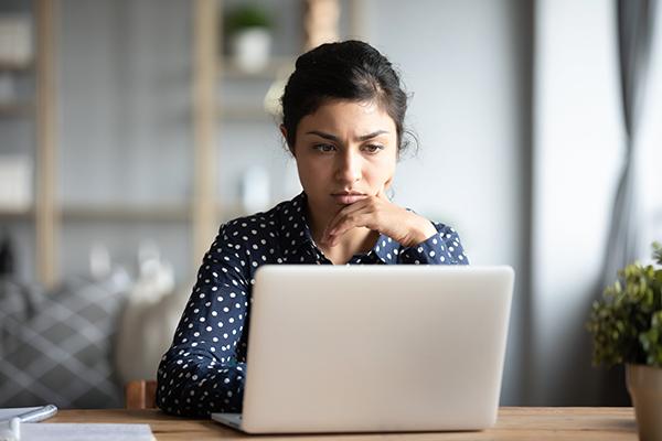 Une femme perplexe devant l’écran de son ordinateur.