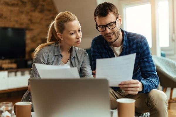 Couple de trentenaires en train de comparer des documents papier.