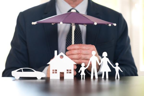 Un parapluie recouvre une maison, une voiture et une famille