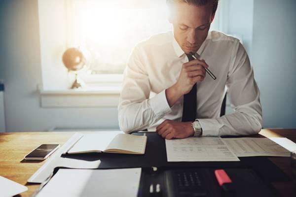 Un homme lit un document en tenant un stylo 