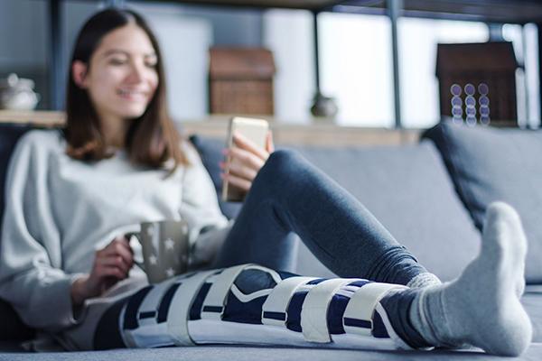 Une jeune femme a une jambe immobilisée dans une attelle