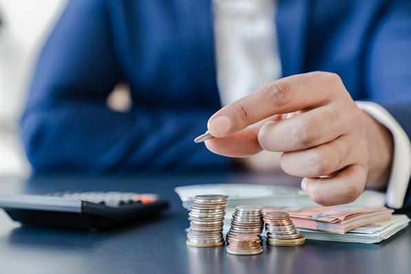 Un homme prend une pièce sur une pile de monnaie et de billets de banque disposée sur une table