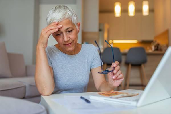 Une femme tant des lunettes devant un contrat et un écran d’ordinateur